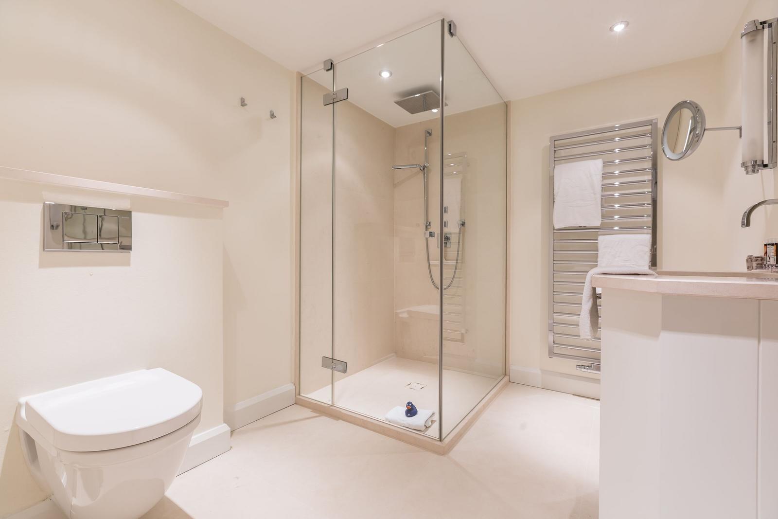 Bathroom with shower, toilet, and towel warmer.