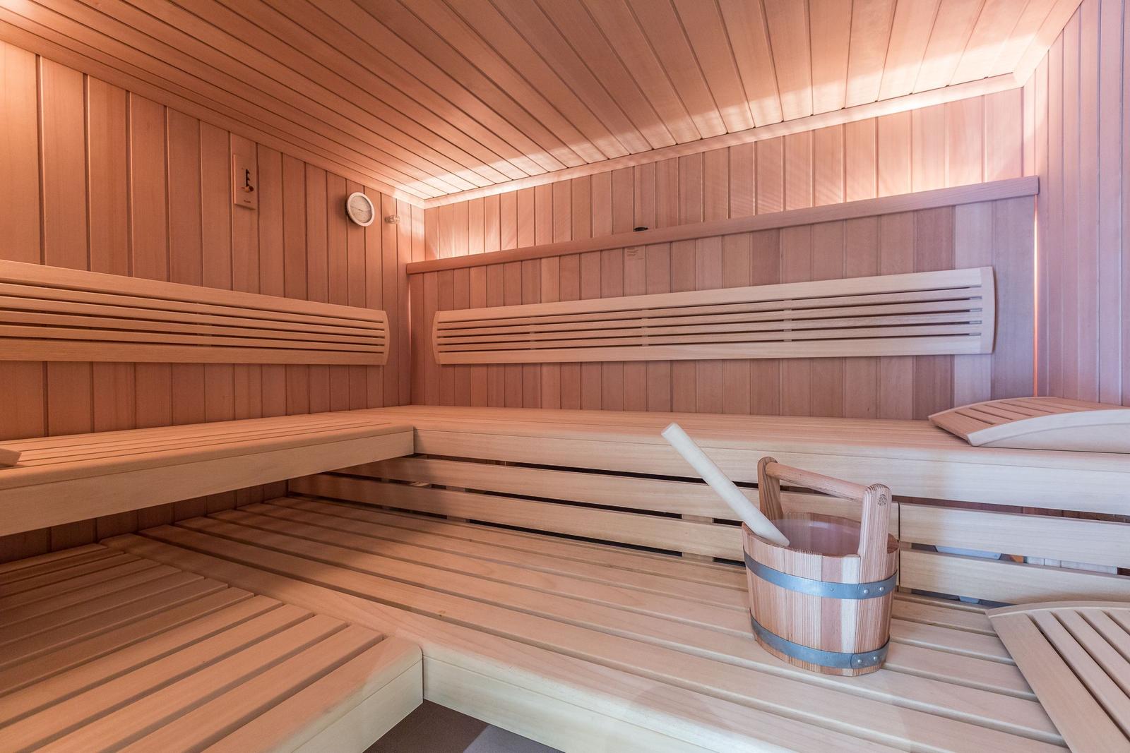 Sauna with wooden bench, thermometer, and bucket with ladle.