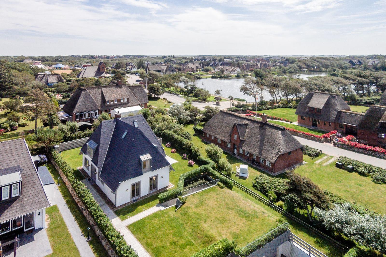 House with roof and garden, surrounded by traditional houses and a lake.