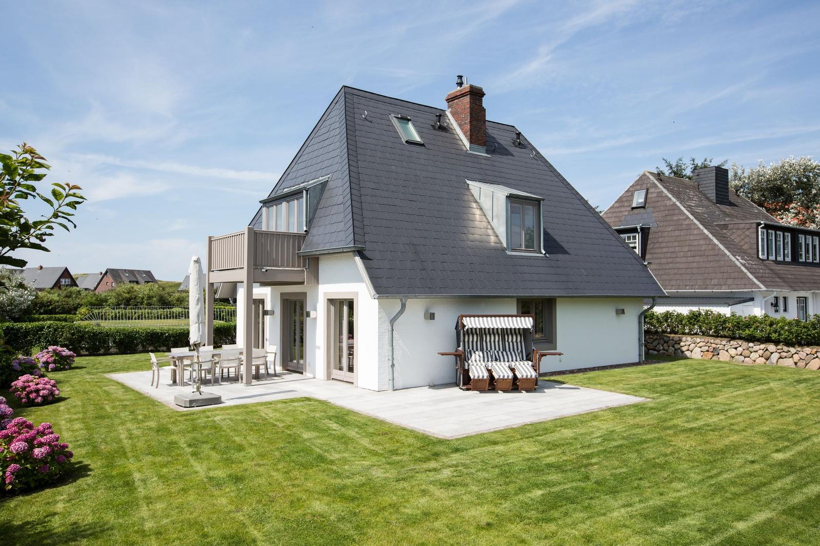 Modern villa with terrace, garden, and sun loungers.