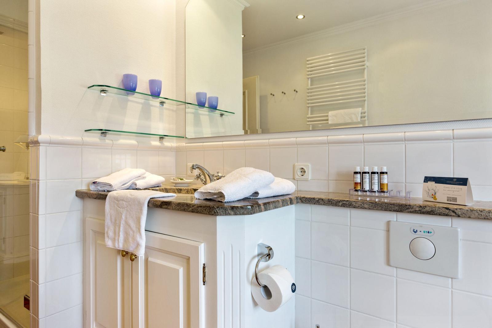Badezimmer mit Waschbecken, Spiegel und Handtuchhalter.