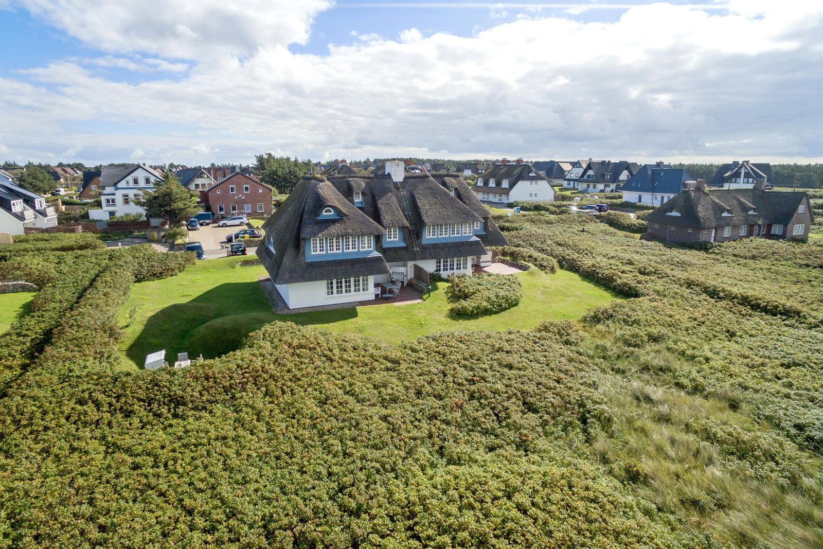 Dorfhaus mit Strohdach und Garten in grüner Landschaft