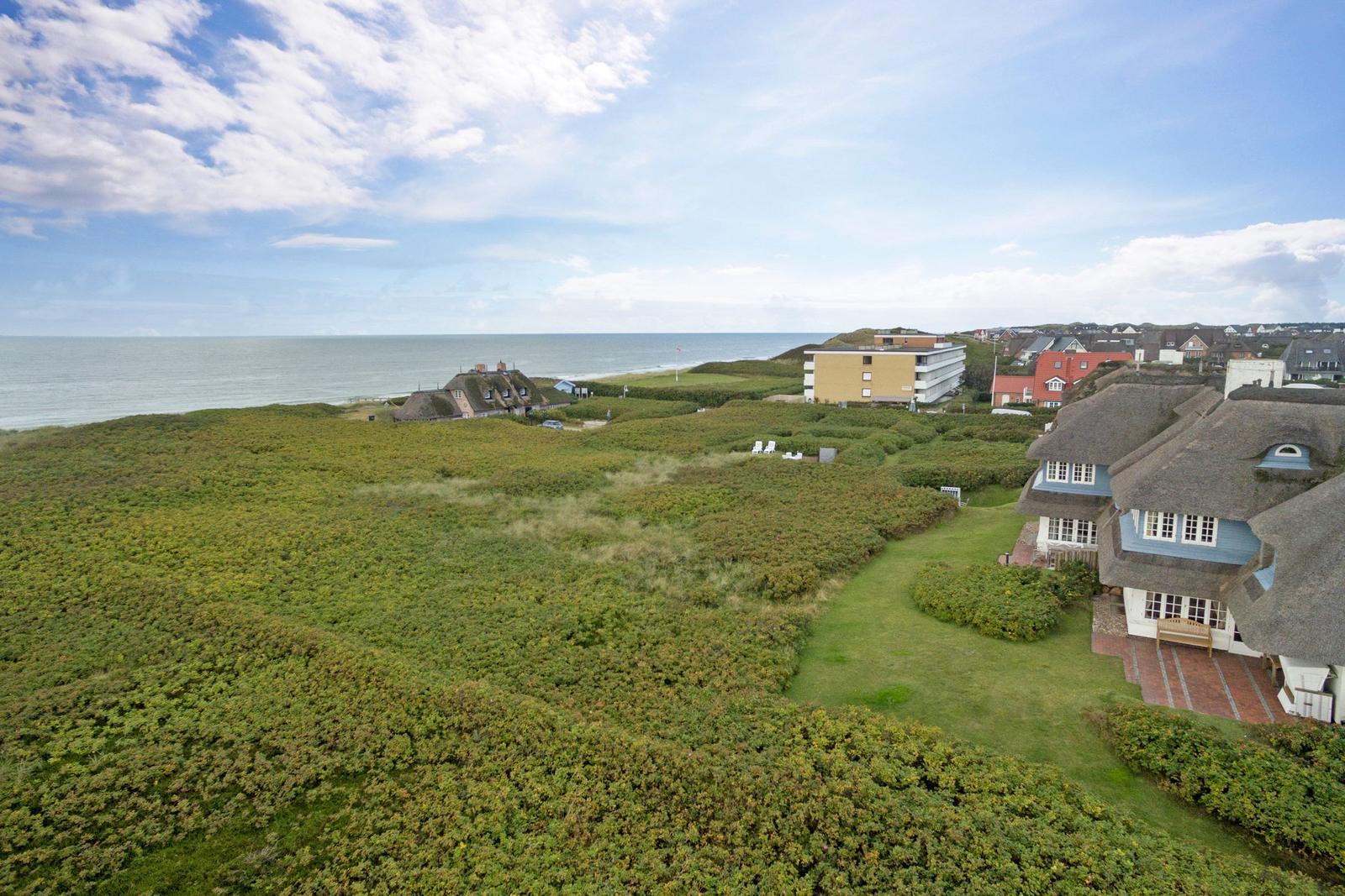 Haus mit Strohdach, Grünfläche und Blick aufs Meer.