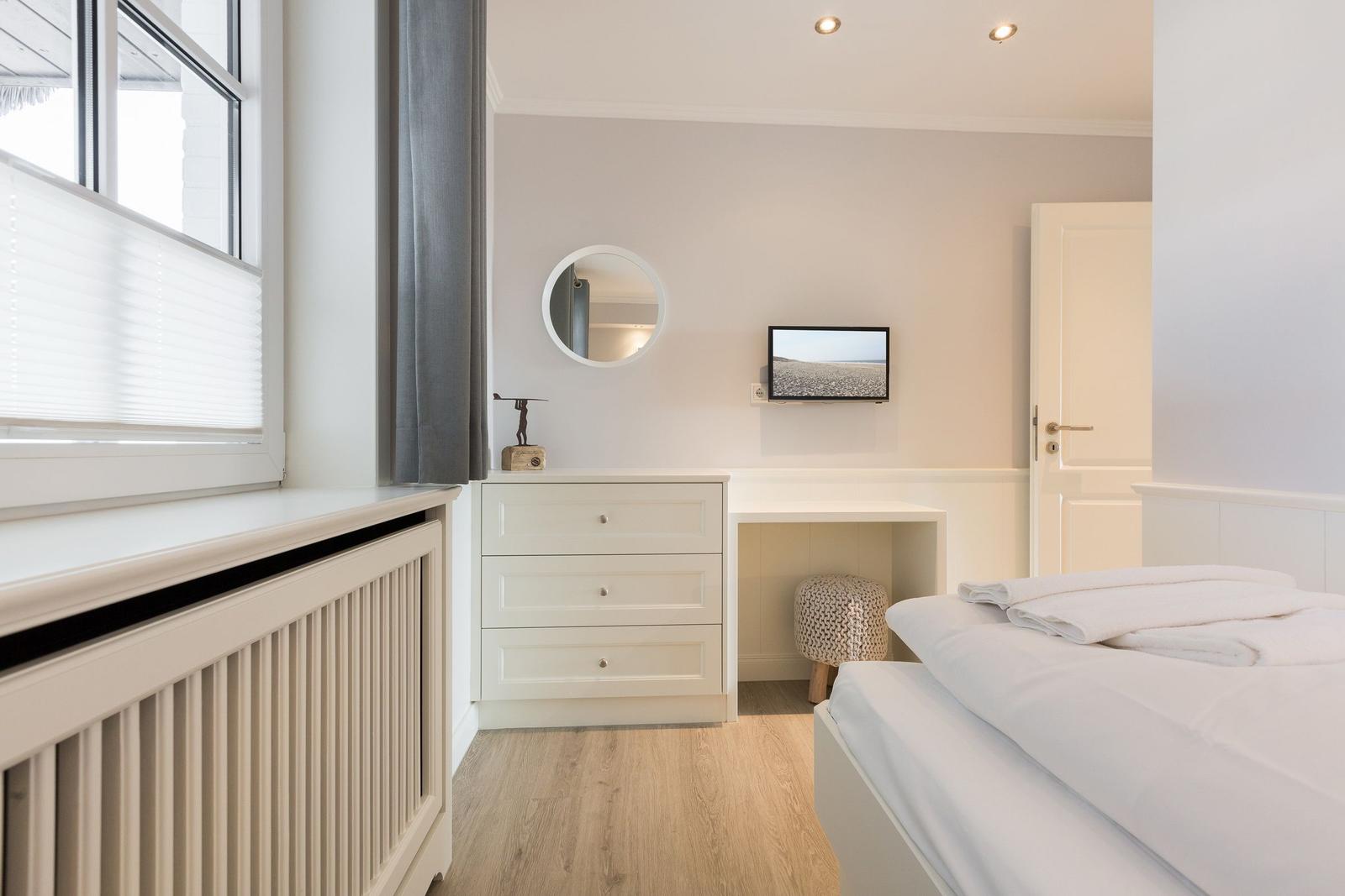 Bedroom with bed, dresser, TV, and window.