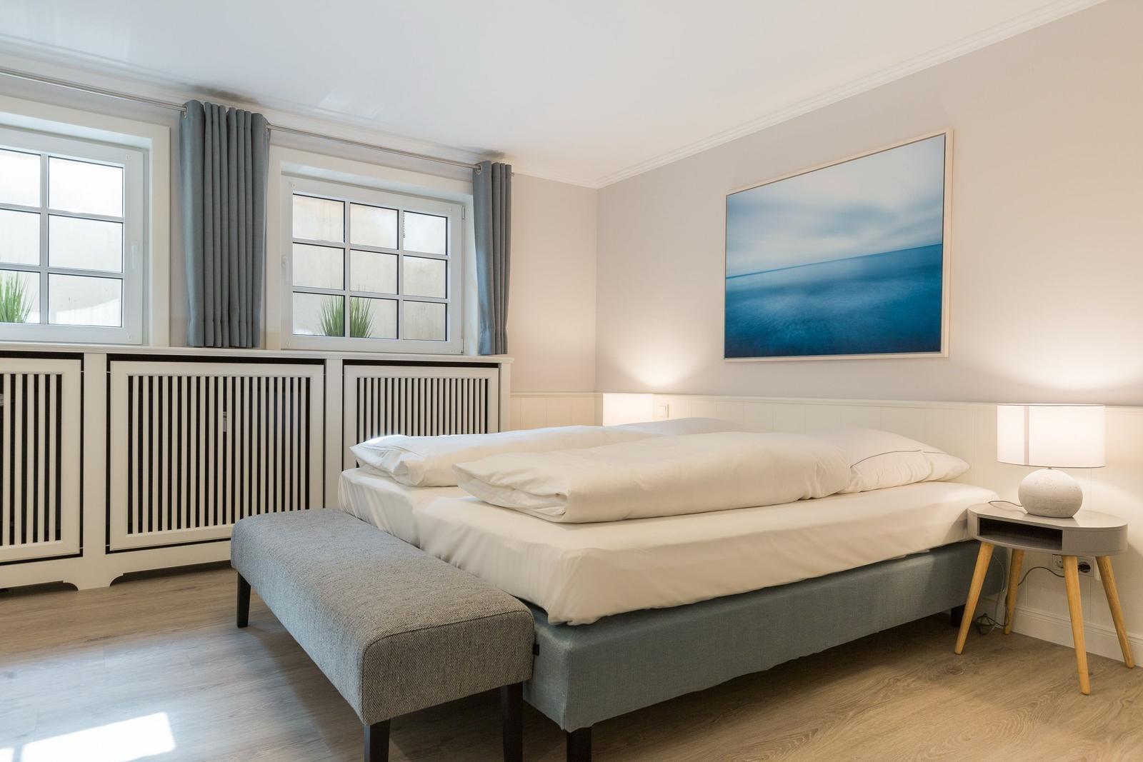 Bedroom with bed, nightstand, and windows.