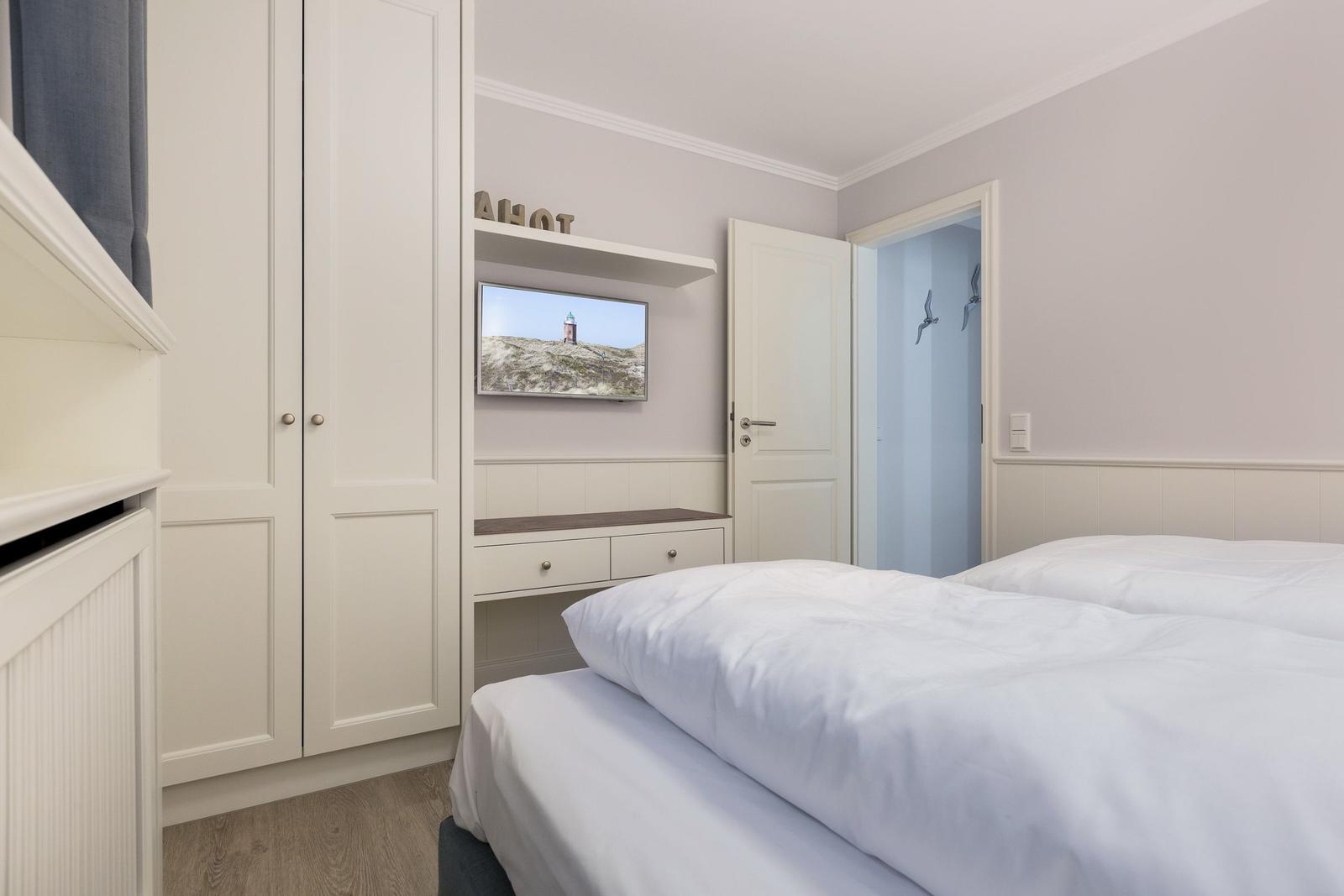 Bedroom with double bed, wardrobe, and TV mounted on the wall.