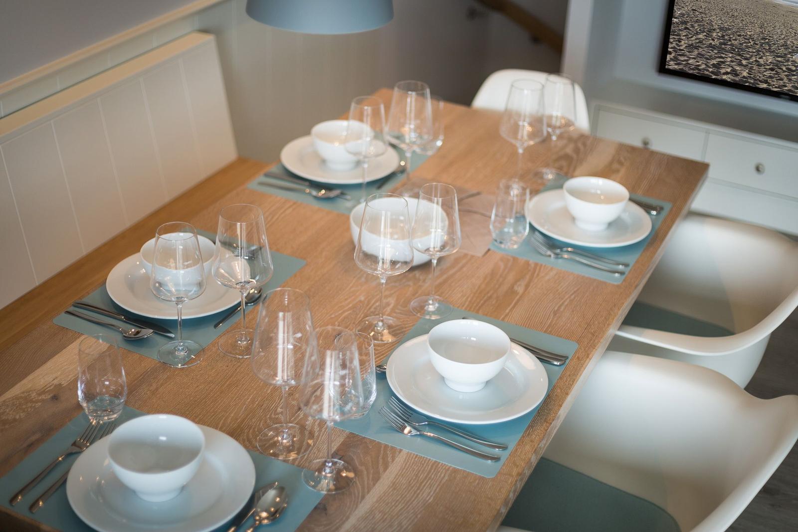 Dining table set for six with modern furnishings.