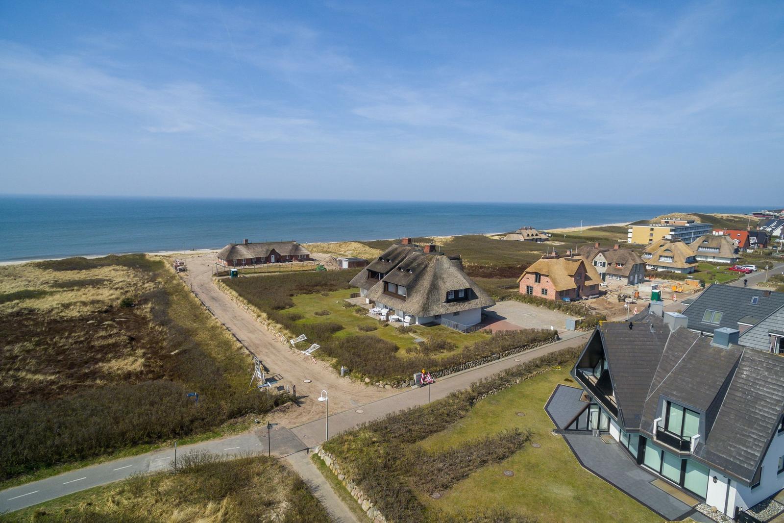 Houses with thatched roofs and modern buildings near the coast.