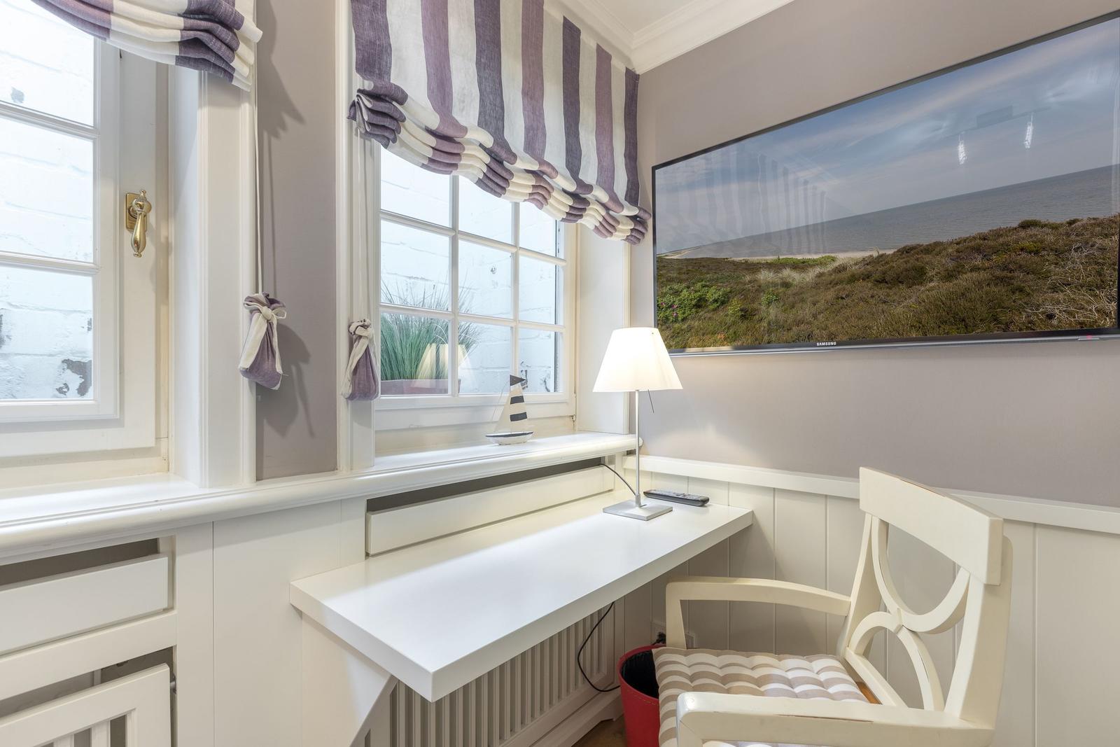 Schreibtisch mit Stuhl unter Fenster, Wandbild und Lampe