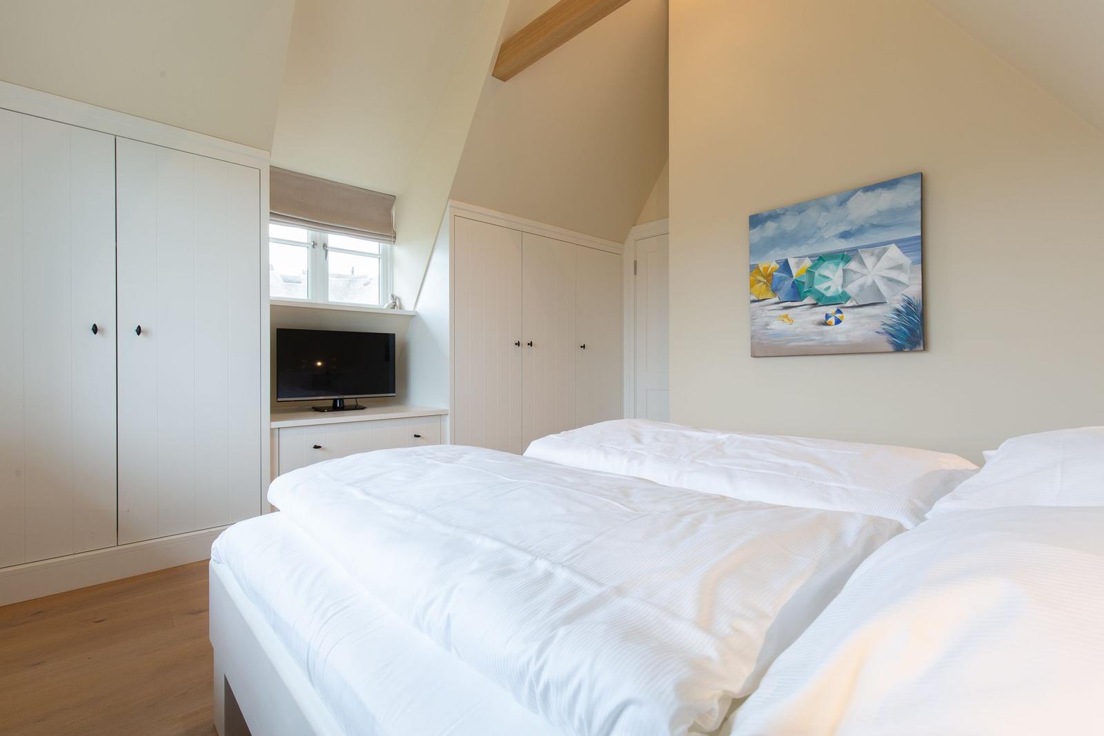 Schlafzimmer mit Doppelbett, Kleiderschränken und Wandbild.