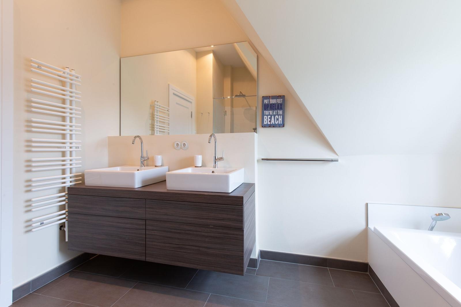Badezimmer mit Doppelwaschbecken, Badewanne und Spiegel
