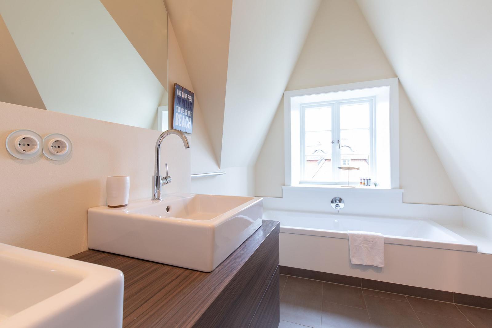 Badezimmer mit Waschbecken, Badewanne und Fenster