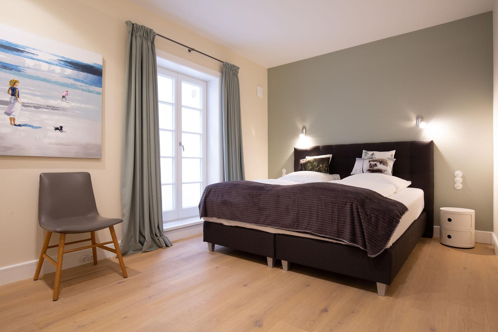 Schlafzimmer mit Bett, Fenster und Stuhl. Wandbild und Beleuchtung.