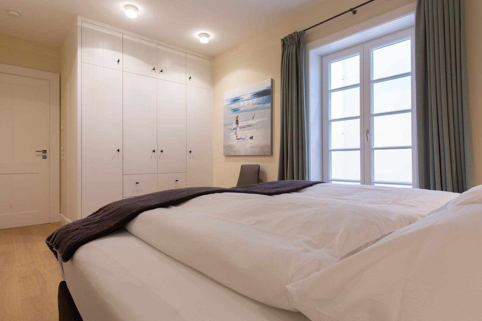 Schlafzimmer mit Bett, Kleiderschrank und Fenster.