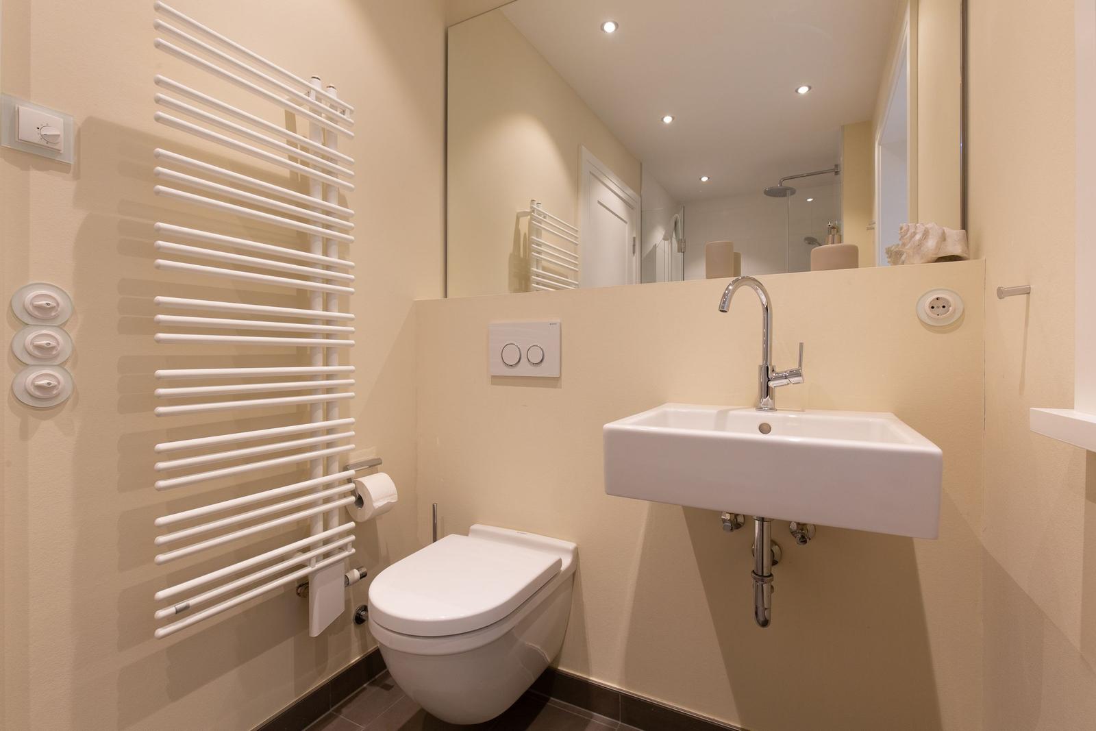 Badezimmer mit Toilette, Waschbecken und Heizkörper.
