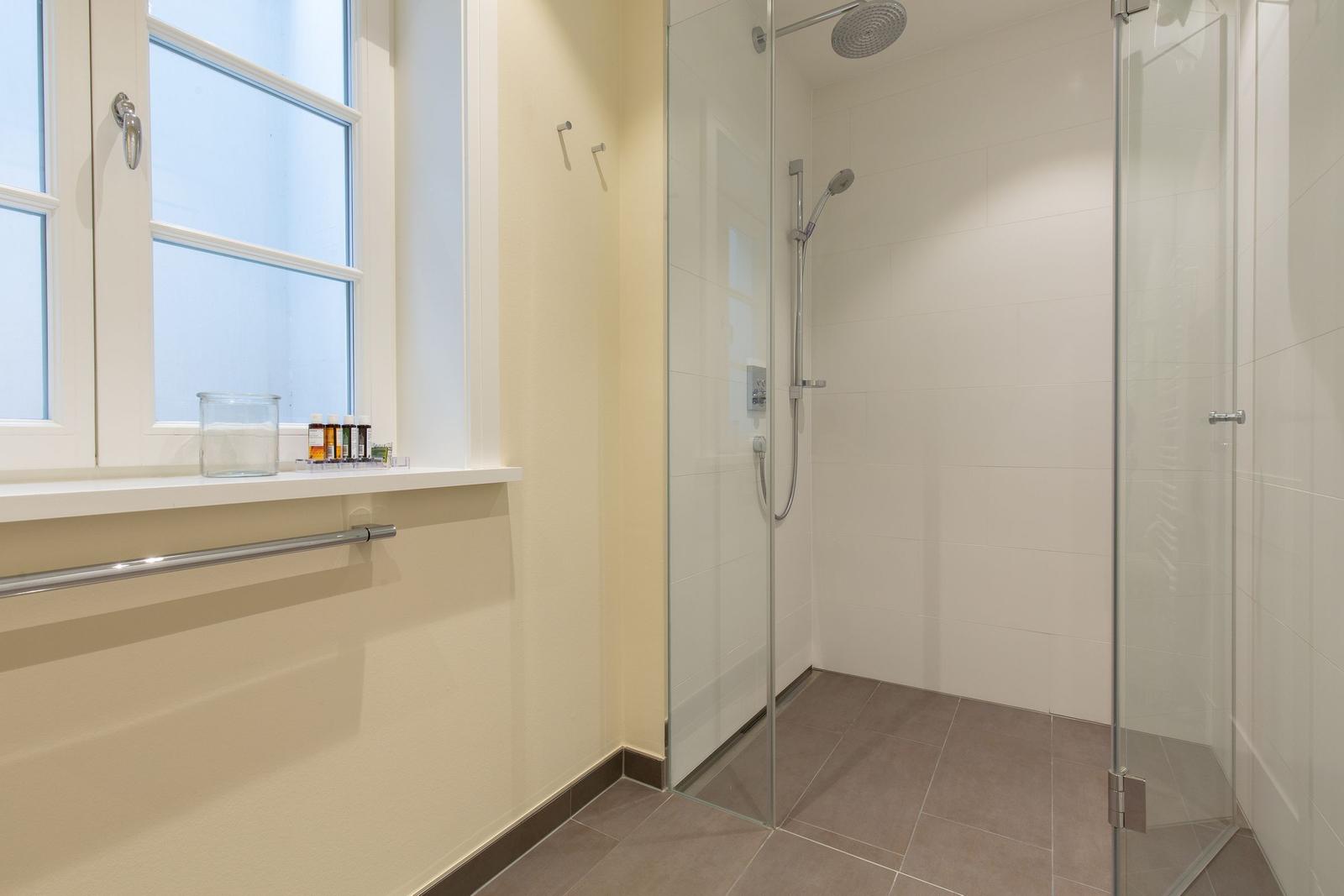 Dusche mit Glaswand, Fenster und Badewannenrand
