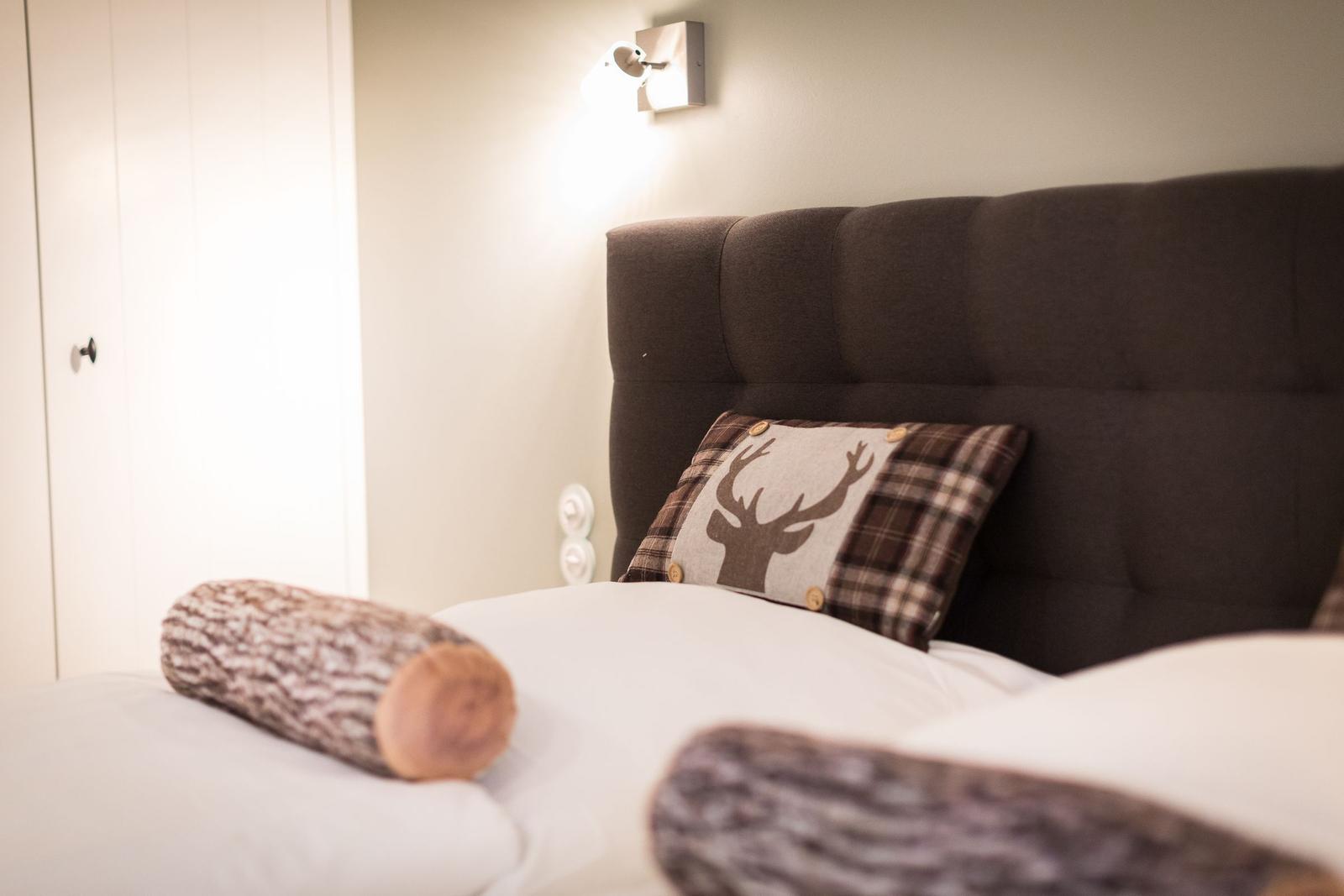 Doppelbett mit Kissen und Holzrollen auf weißer Bettwäsche