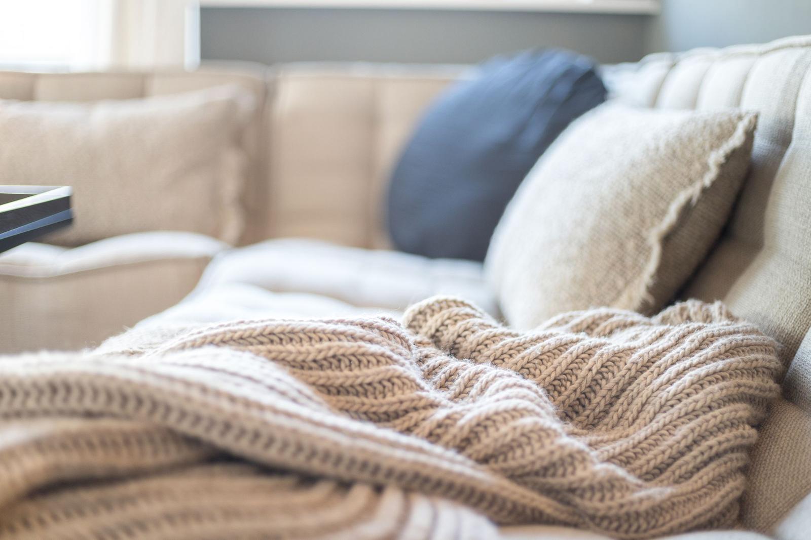 Ein Sofa mit Kissen und einer gestrickten Decke.