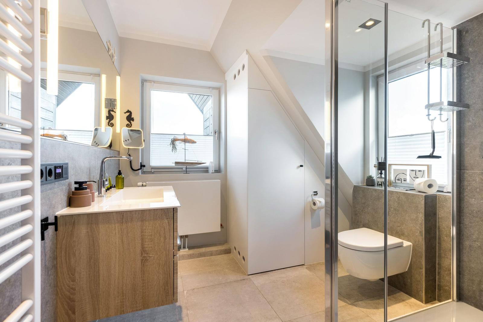 Badezimmer mit Dusche, Waschbecken und Toilette unter Dachschräge