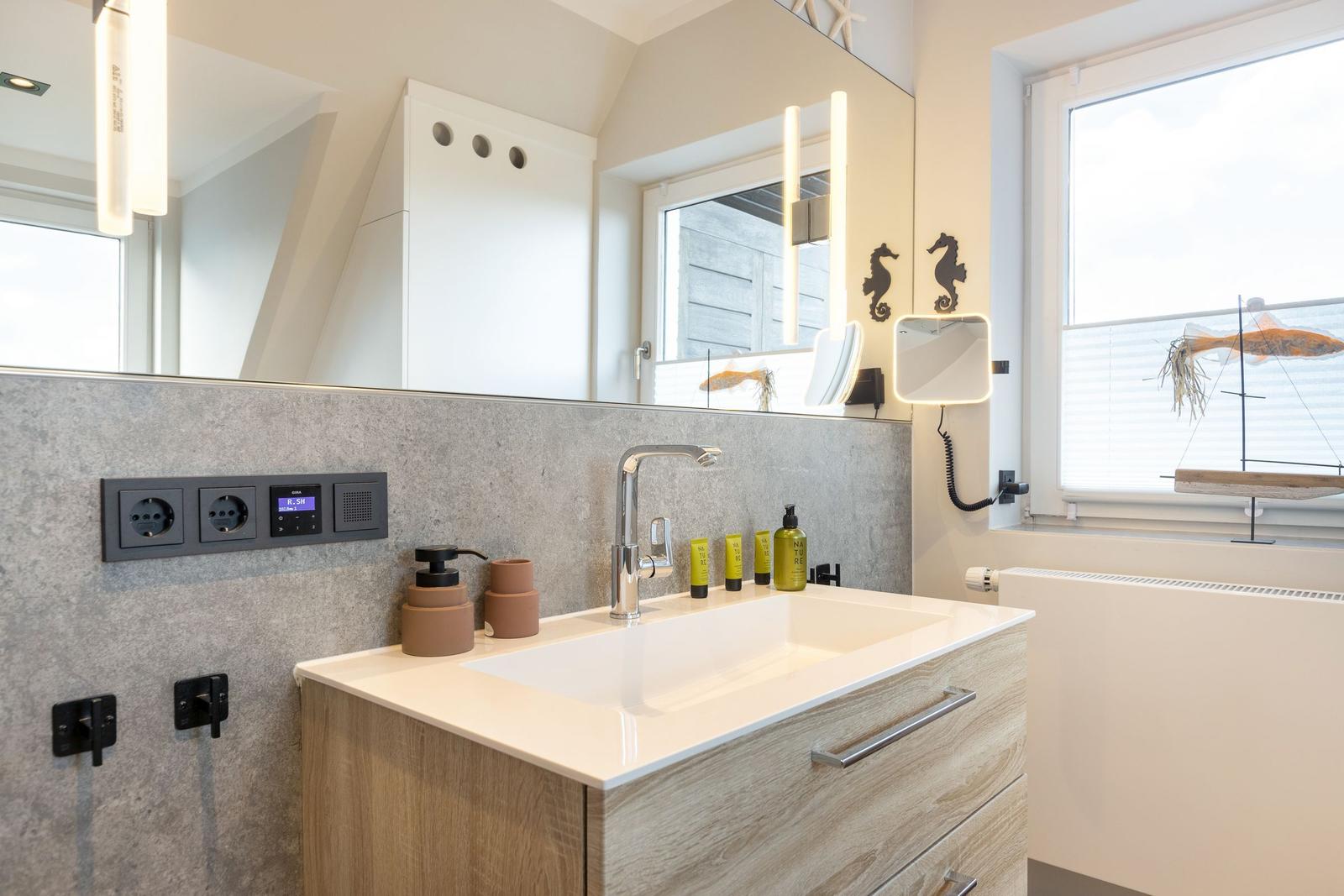 Badezimmer mit Waschtisch, Spiegel und Fenster