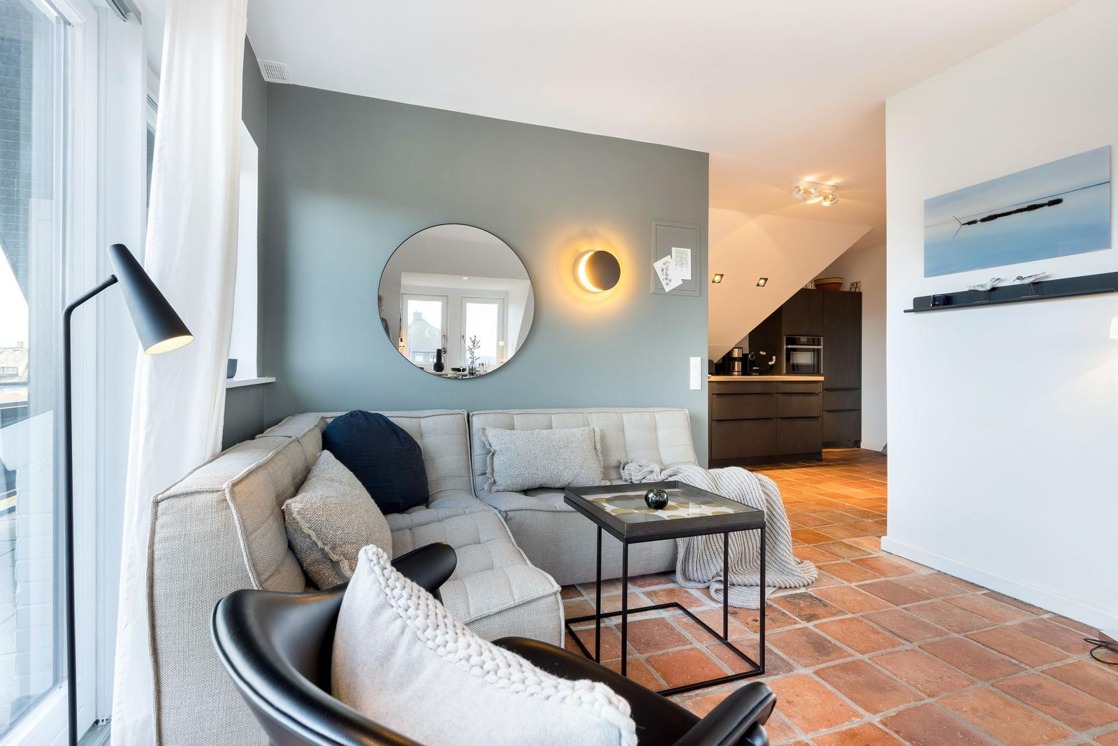 Wohnzimmer mit Sofa, Couchtisch und Küchenbereich im Hintergrund.