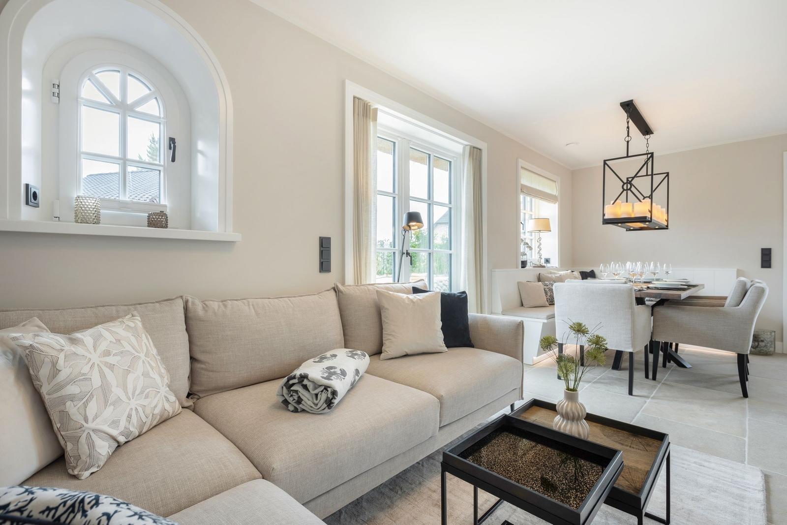 Living and dining area with sofa, table, and windows.