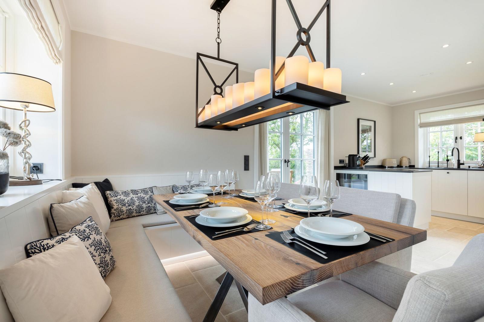 Dining room with wooden table, bench, and modern pendant light.