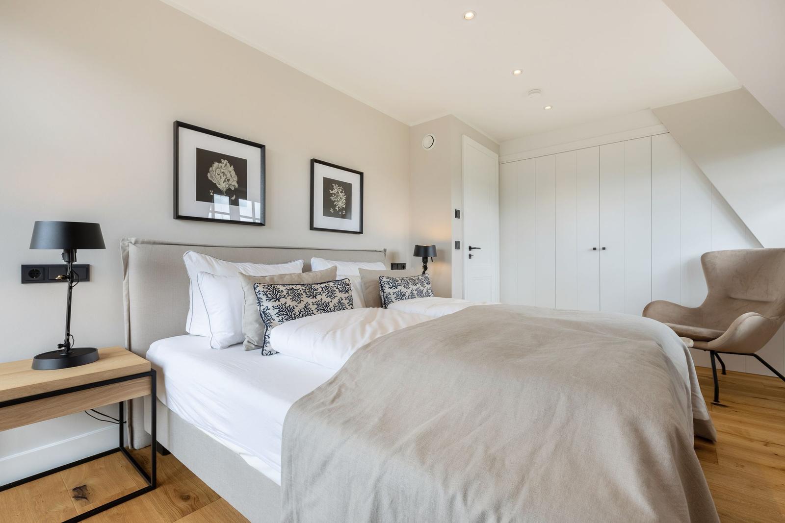 Bedroom with double bed, wardrobe, and armchair.