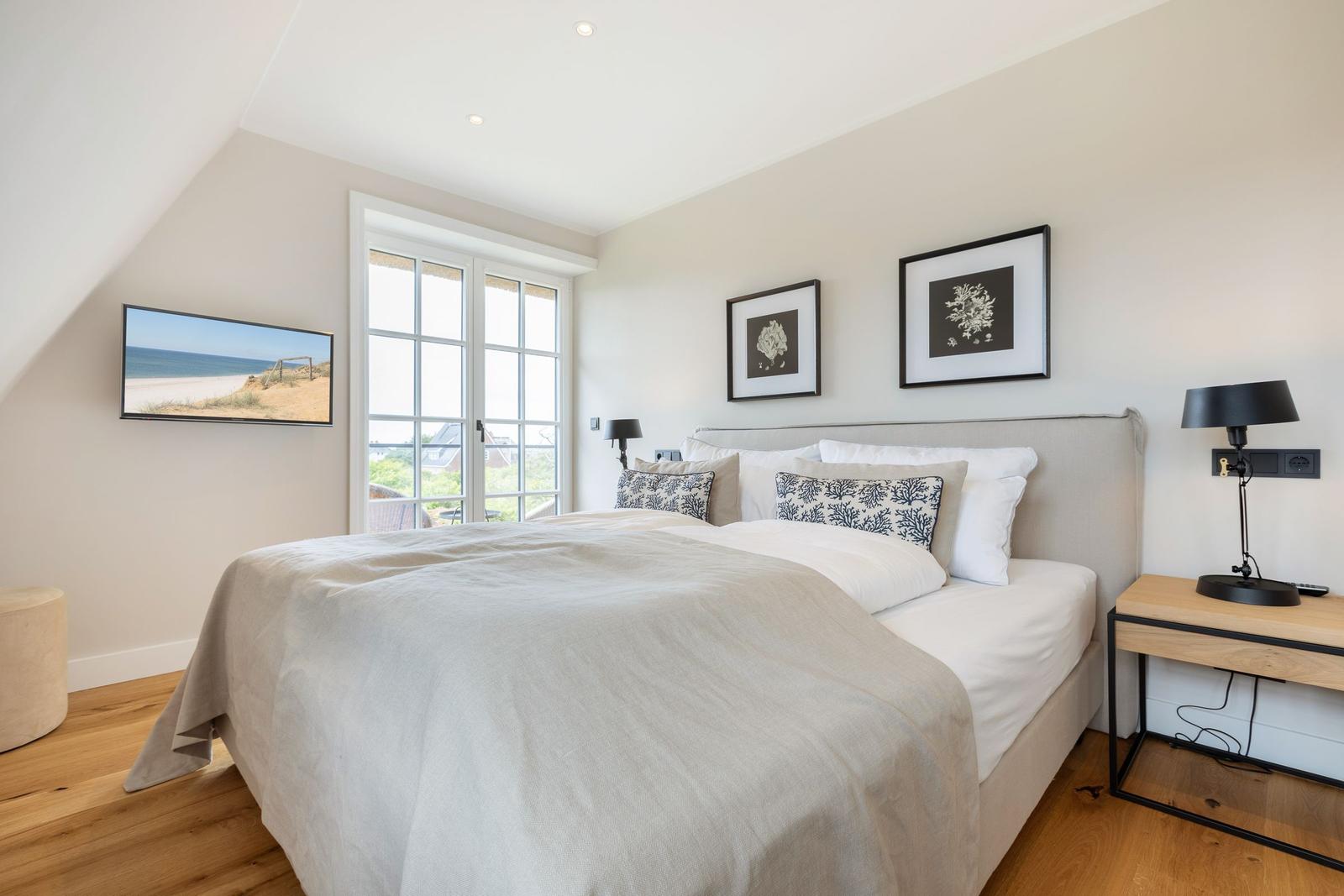 Bedroom with bed, window, and wall pictures