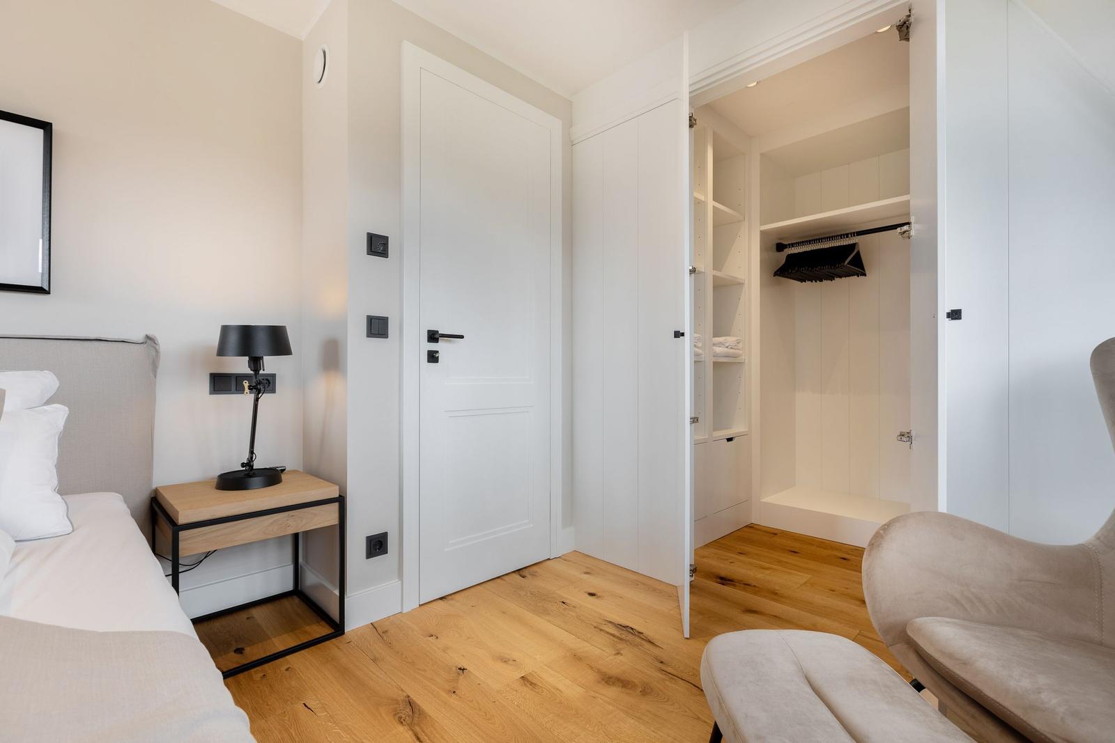 Bedroom with bed, nightstand, closet, and chair.