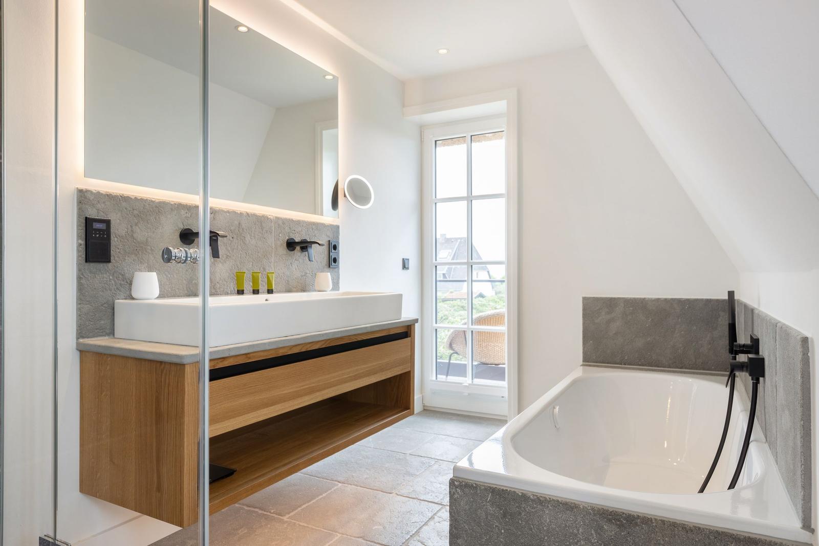 Bathroom with bathtub, sink, and shower. Window with view.