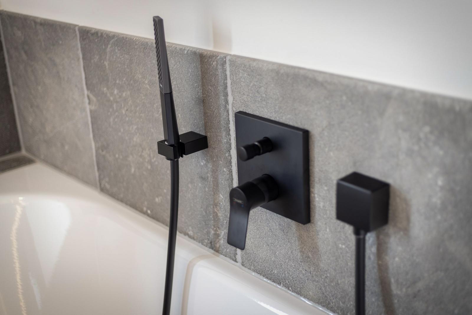 Showerhead and faucets mounted on wall above bathtub