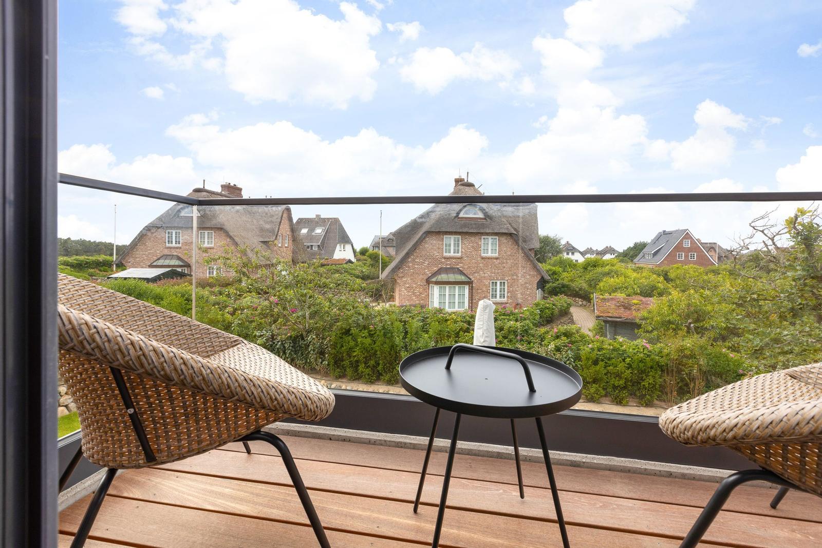 Terrace with chair and table, view of traditional houses with thatched roofs.