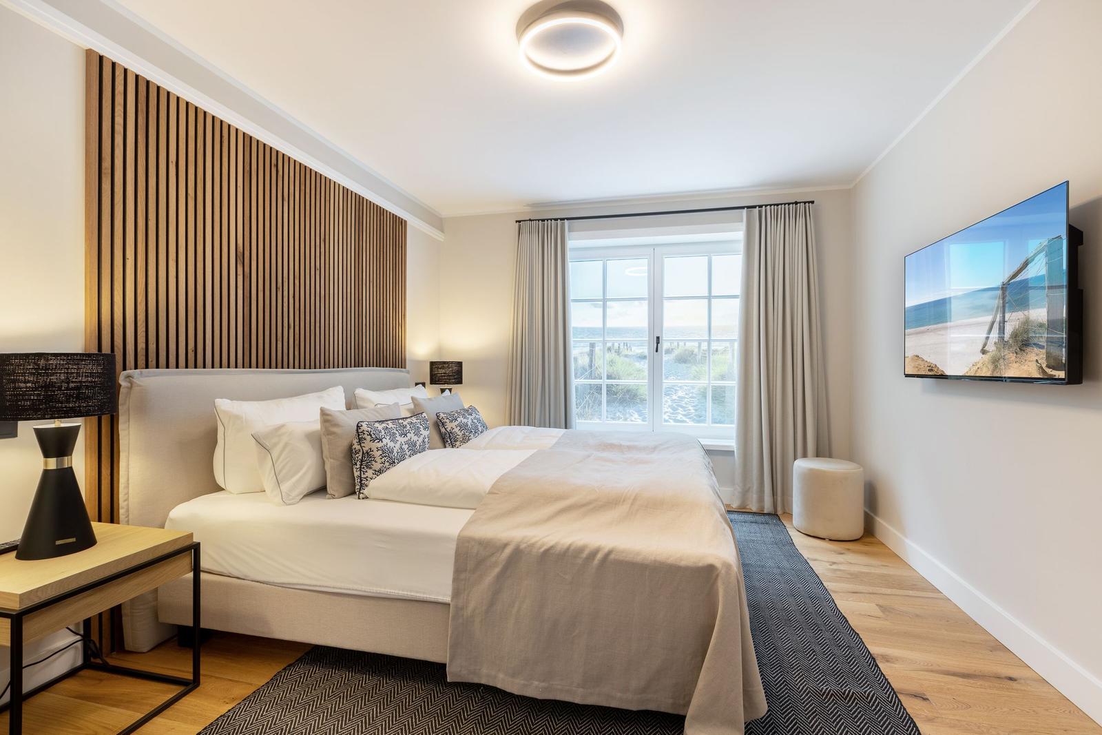 Bedroom with bed, window view, and wall-mounted TV.