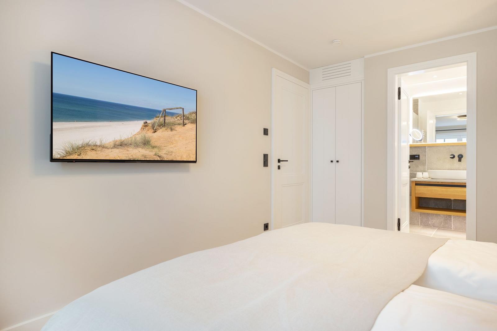 Bedroom with bed, TV, and access to bathroom.