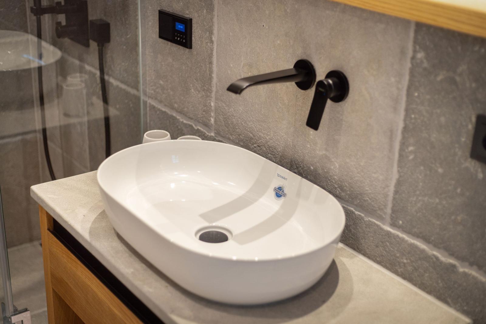 Sink with black faucet and gray wall