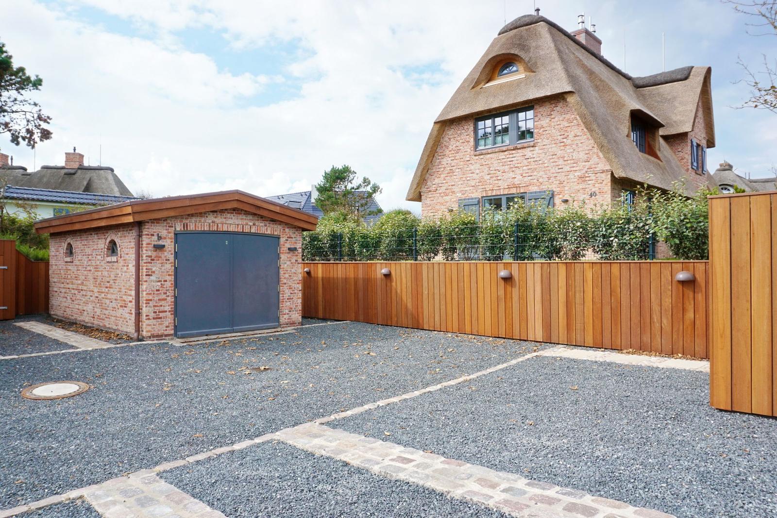 House with thatched roof, wooden fence, and gravel area