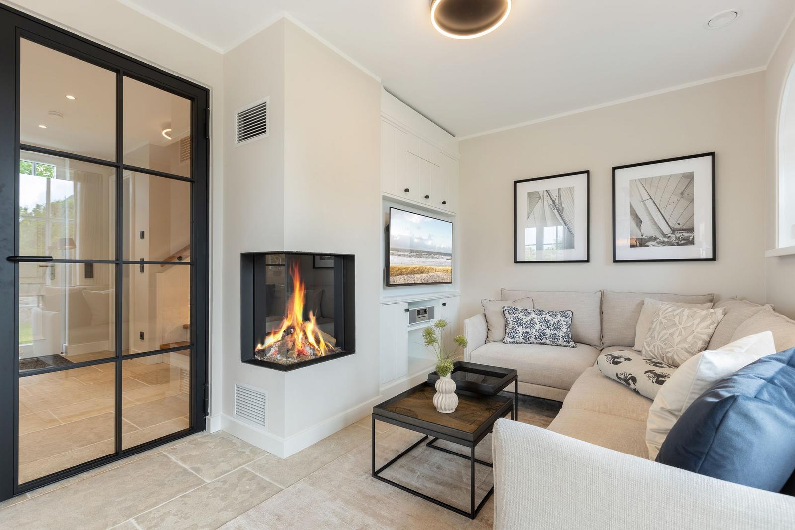 Living room with fireplace, sofa, and TV. Door leads to adjacent room.