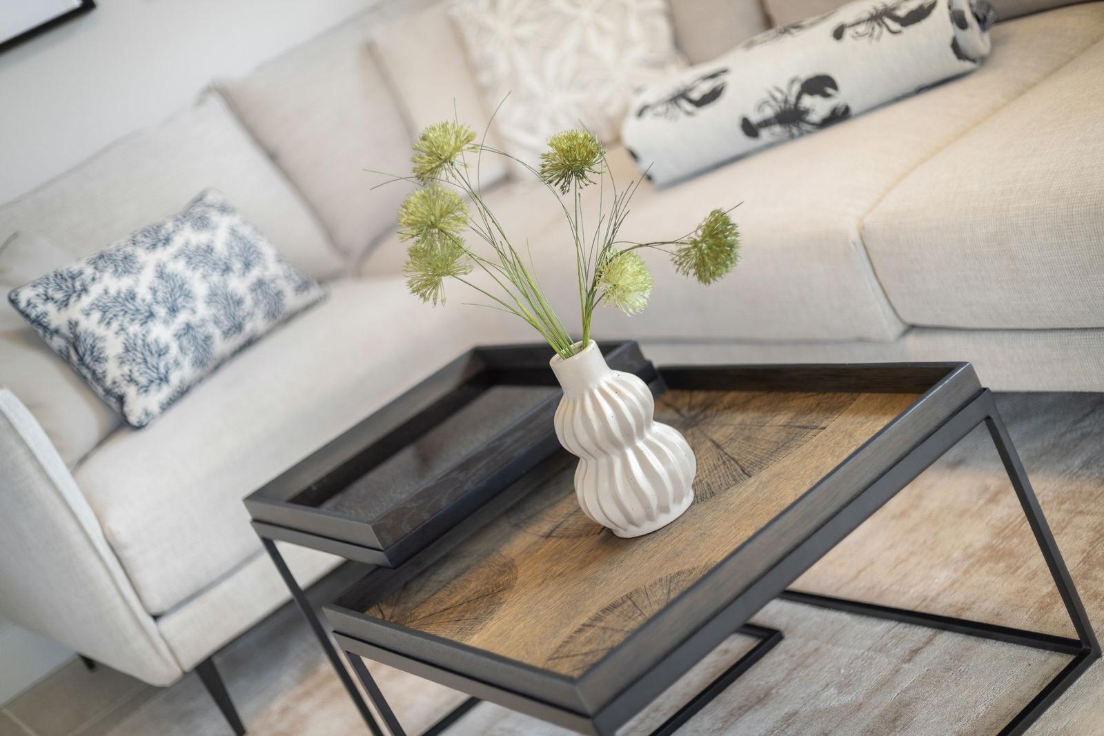 Living area with sofa, cushions, and a coffee table with vase.