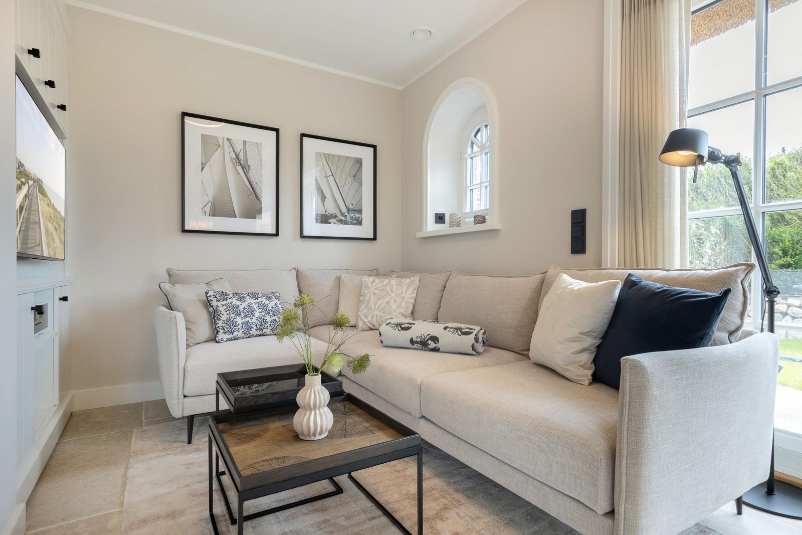 Living room with sofa, coffee table, and window. Wall art and floor lamp visible.