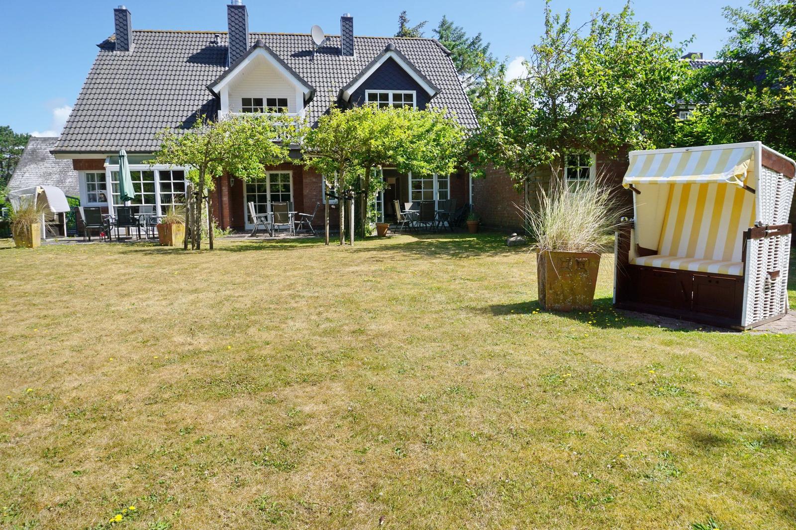 House with large garden and beach chair in foreground.