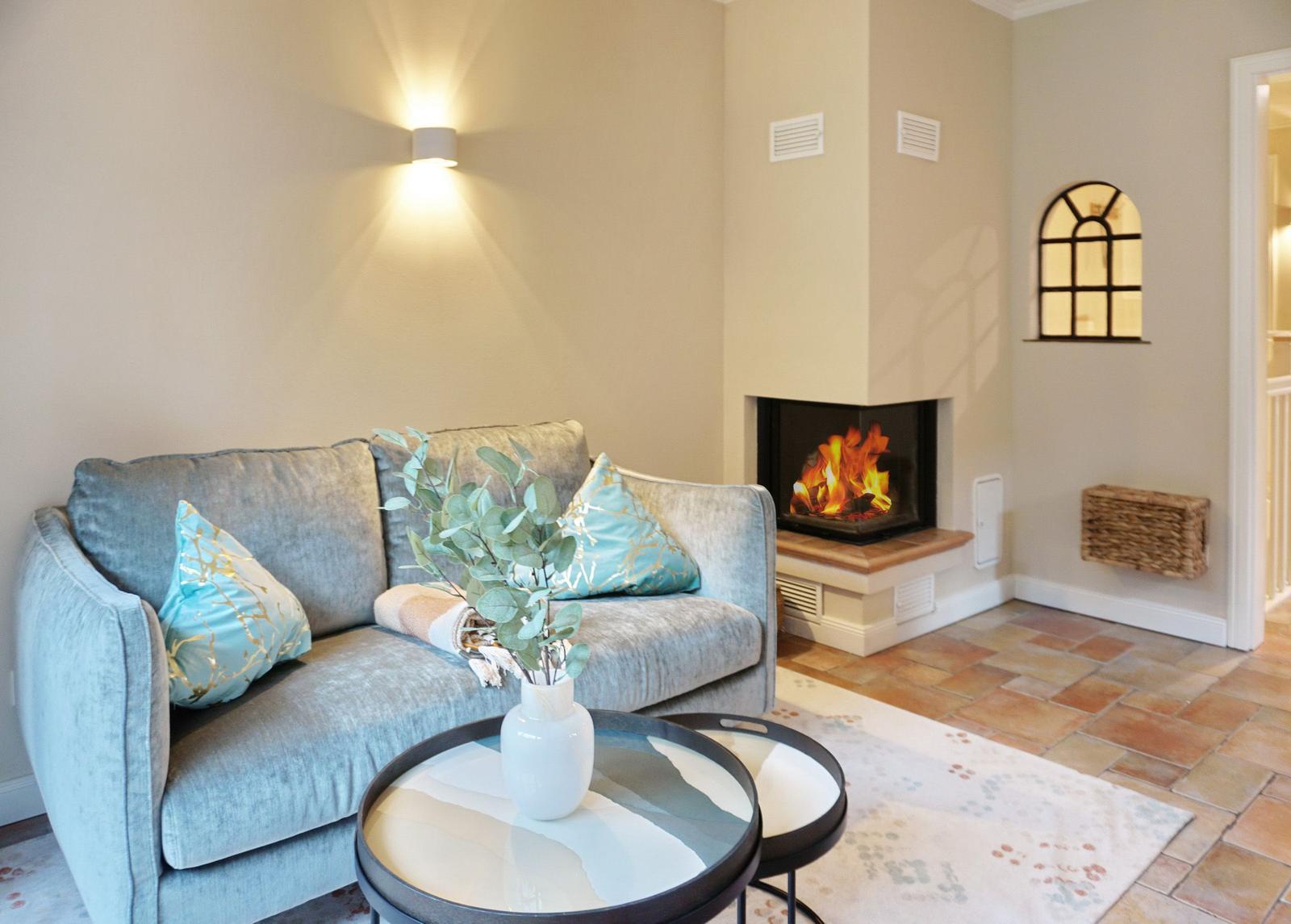 A living room with sofa, fireplace, and round tables.