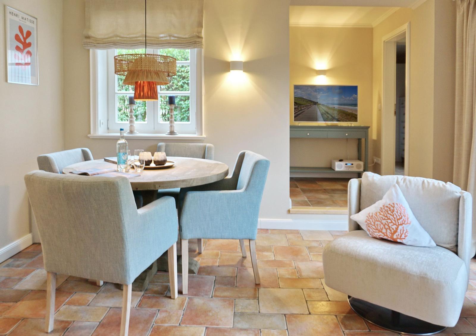 Round table with chairs, armchair and window in dining room.
