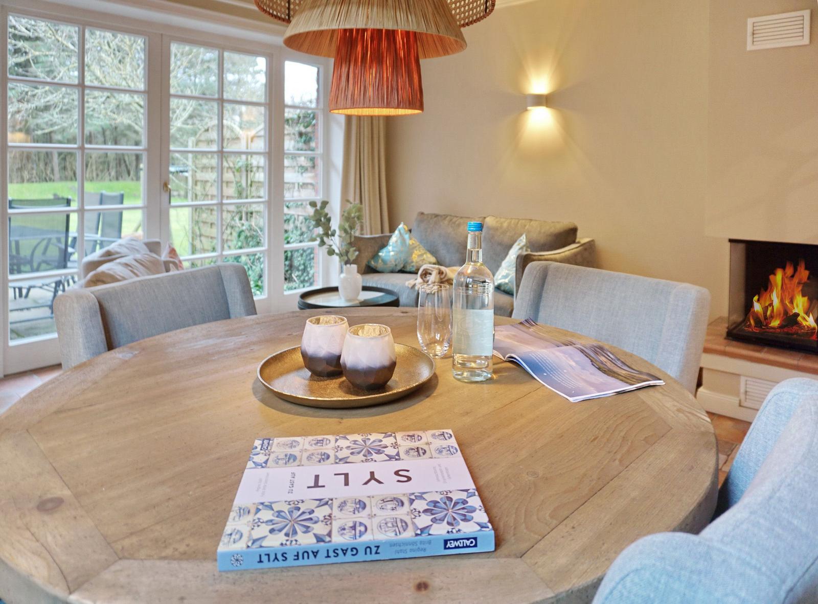 Round table with bottle and glasses, fireplace and seating area in room.