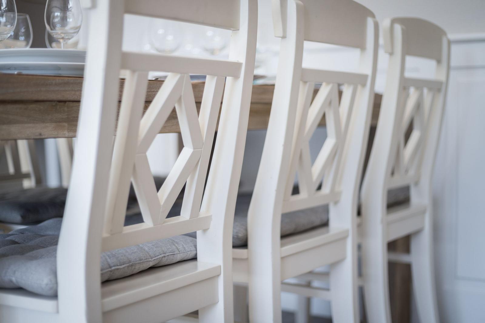 White chairs with gray cushions around a wooden table.
