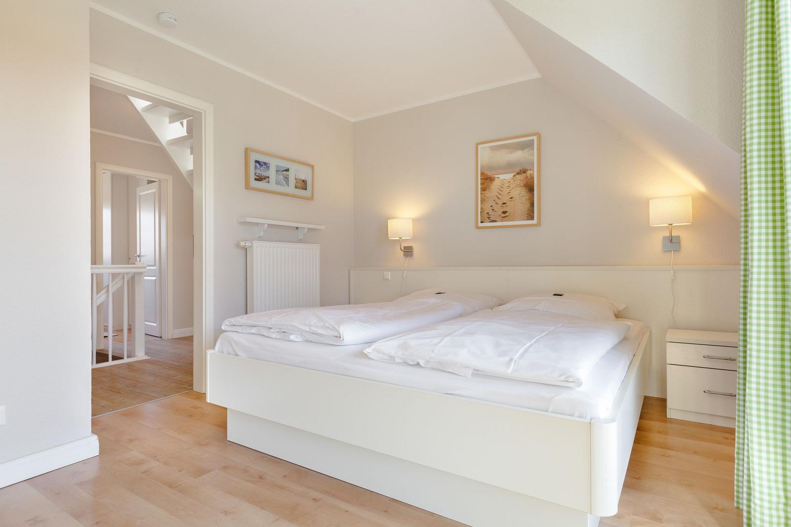 Bedroom with double bed, wall lamps, and view into the staircase.