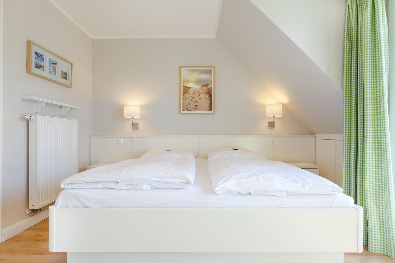 Bedroom with double bed, two nightstands, and green checkered curtains.
