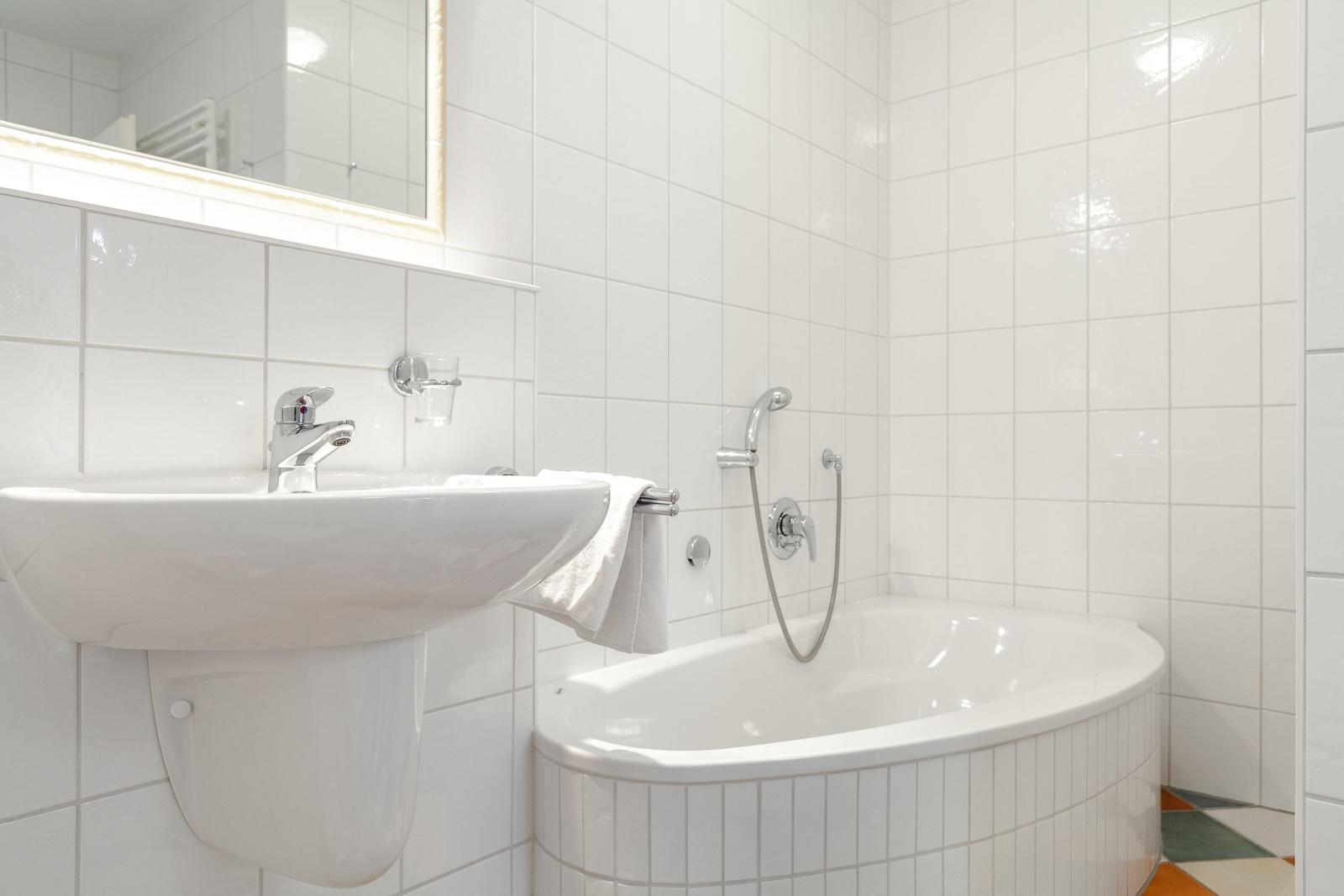 Bathroom with bathtub, sink, and mirror.
