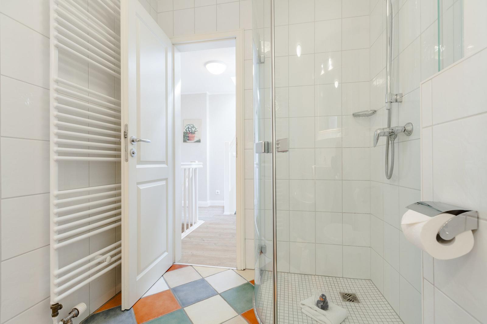 Bathroom with shower, heater, and colorful floor tile pattern.