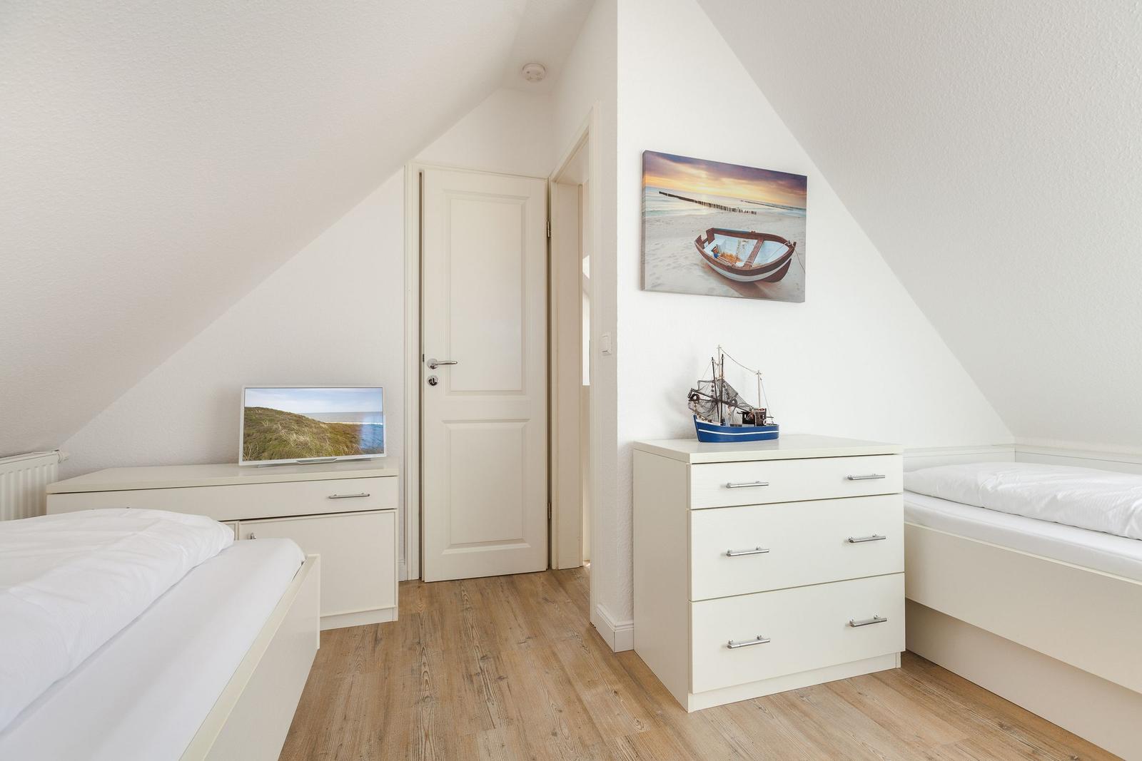 Room with two beds, dresser, and wall picture with boat.